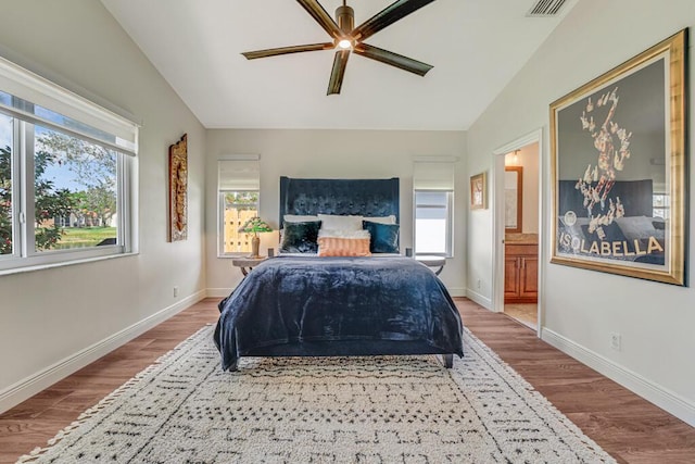 bedroom with vaulted ceiling, multiple windows, and wood finished floors