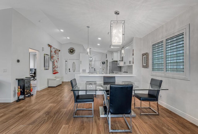 dining area with baseboards, vaulted ceiling, and wood finished floors