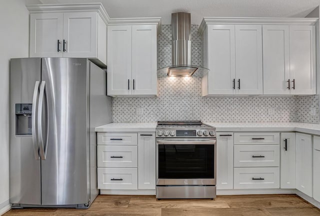 kitchen featuring light countertops, white cabinets, stainless steel appliances, and wall chimney exhaust hood