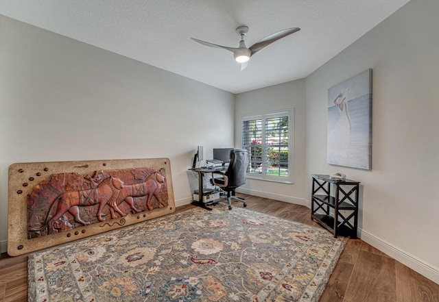 office area with a ceiling fan, baseboards, and wood finished floors