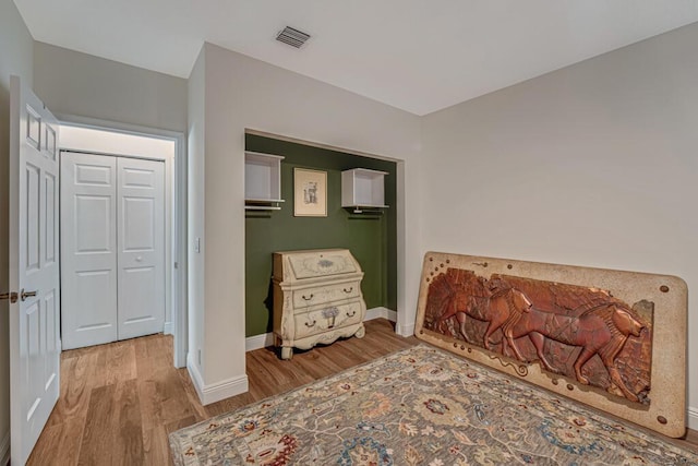 bedroom featuring baseboards, wood finished floors, and visible vents