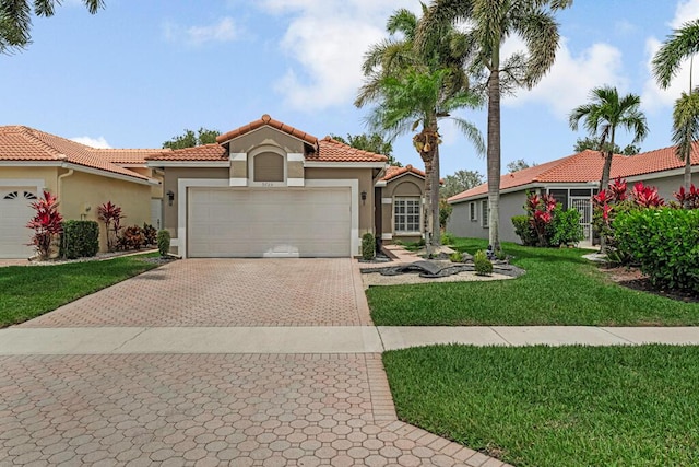 mediterranean / spanish-style home with a tile roof, a garage, decorative driveway, a front lawn, and stucco siding