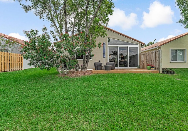 rear view of house with fence, stucco siding, and a lawn