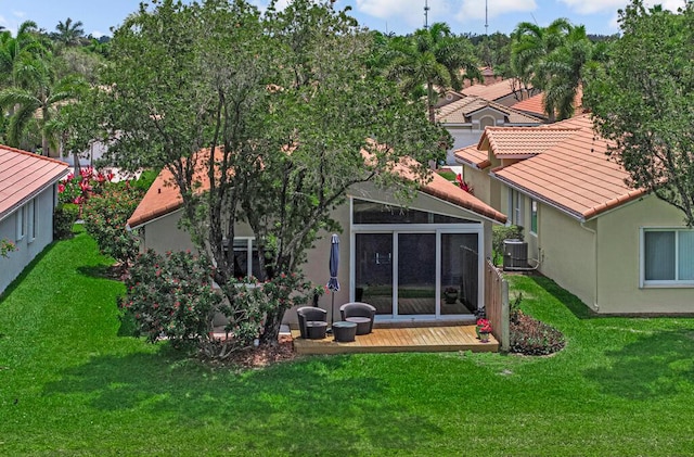 rear view of house with a lawn, a wooden deck, a tiled roof, and stucco siding