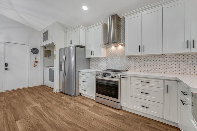 kitchen with wall chimney range hood, appliances with stainless steel finishes, visible vents, and light countertops