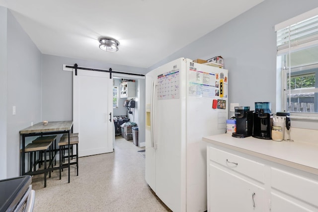 2136 W Carrol Cir, West Palm Beach, FL 33415 - kitchen with white fridge with ice dispenser, a barn door, dark aggregate flooring, white cabinets, and light countertops