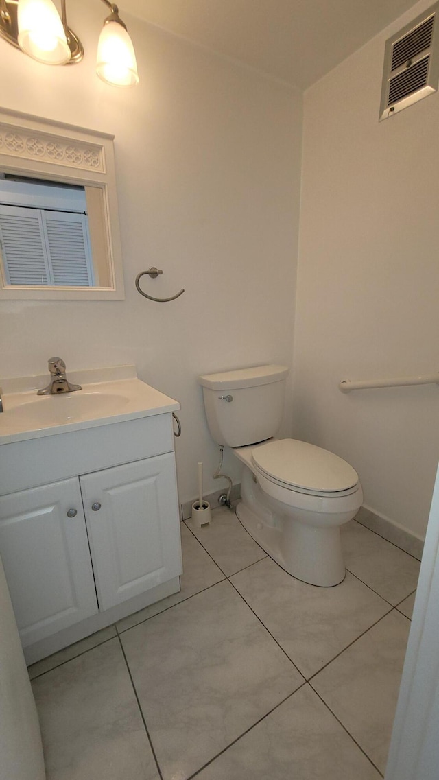 half bath with toilet, tile patterned flooring, vanity, and baseboards