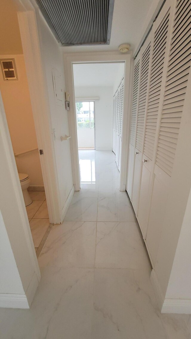corridor with light marble finish floors and baseboards