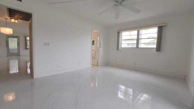 spare room featuring marble finish floors, ceiling fan, and baseboards