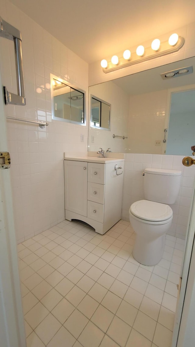 bathroom featuring tile walls, tile patterned floors, toilet, and vanity