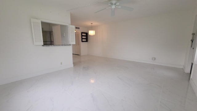 empty room featuring ceiling fan, light marble finish floors, a chandelier, and baseboards