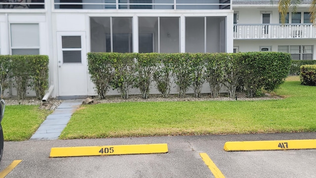 doorway to property with uncovered parking and a yard