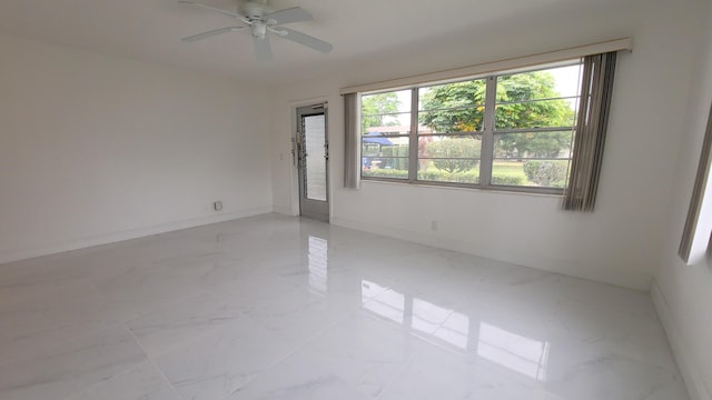 spare room with light marble finish floors, ceiling fan, and baseboards