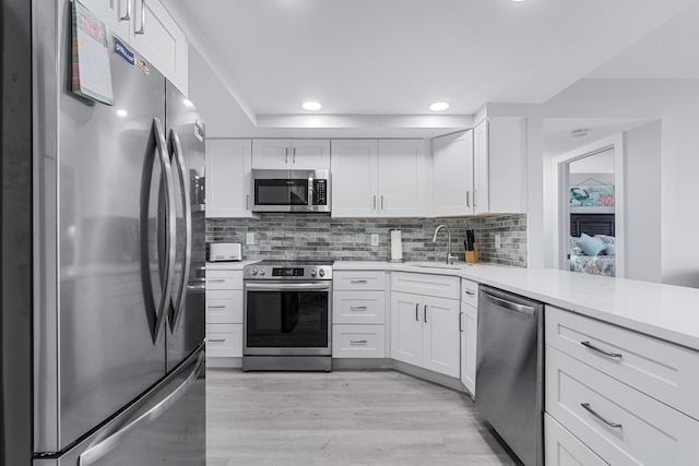 kitchen featuring light countertops, appliances with stainless steel finishes, a sink, and white cabinetry