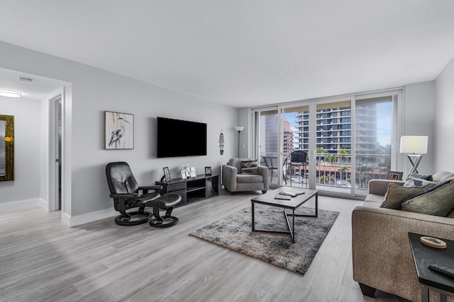 living room featuring a wall of windows, baseboards, and wood finished floors