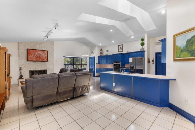 living room featuring light tile patterned floors, vaulted ceiling with skylight, and a fireplace