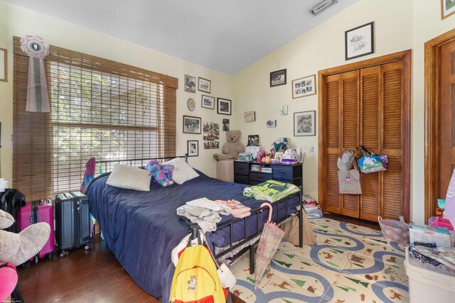 bedroom featuring visible vents, wood finished floors, lofted ceiling, and a closet