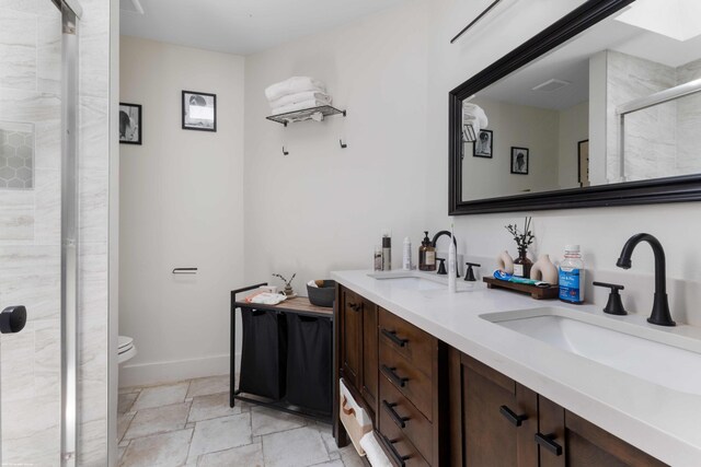 full bath with a sink, stone finish floor, a stall shower, and double vanity