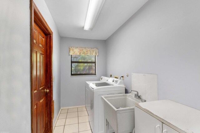 washroom with washer and dryer, baseboards, a sink, cabinet space, and light tile patterned floors