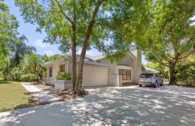 view of property exterior featuring an attached garage, stucco siding, a chimney, and concrete driveway
