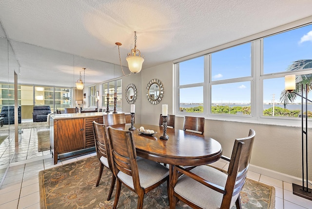 5440 N Ocean Dr Unit 202, Singer Island, FL 33404 - dining space featuring baseboards, a textured ceiling, light tile patterned flooring, and a healthy amount of sunlight