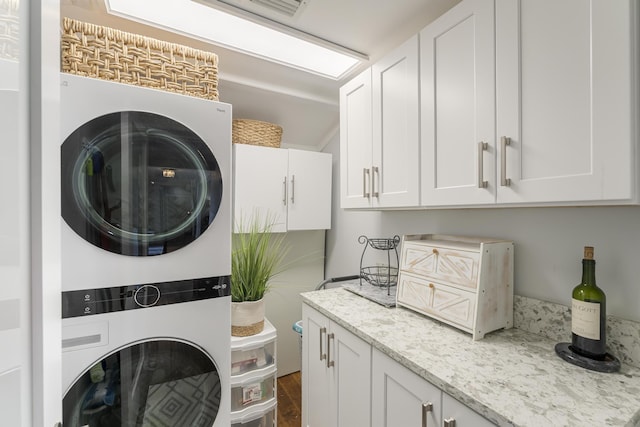 clothes washing area with stacked washing maching and dryer, dark wood-style flooring, and cabinet space
