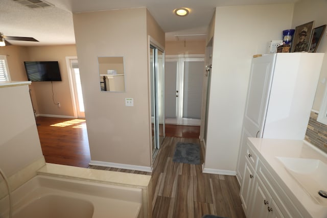 7175 NW 82nd Ct, Okeechobee, FL 34972 - full bathroom featuring wood finished floors, a ceiling fan, a bath, visible vents, and baseboards