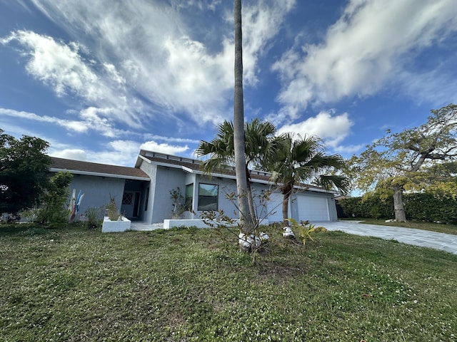 view of front facade with concrete driveway, a garage, a front yard, and stucco siding