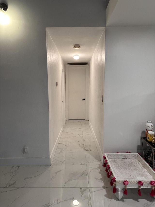 corridor with baseboards and marble finish floor
