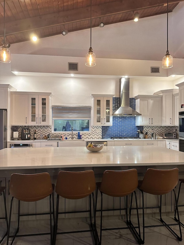 kitchen featuring light countertops, wall chimney exhaust hood, wooden ceiling, backsplash, and visible vents