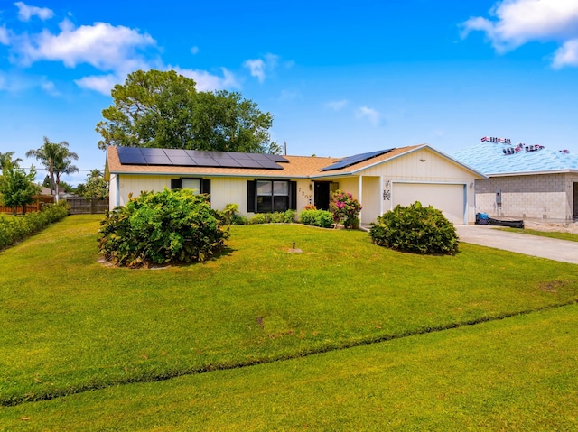 single story home with fence, an attached garage, a front yard, solar panels, and driveway