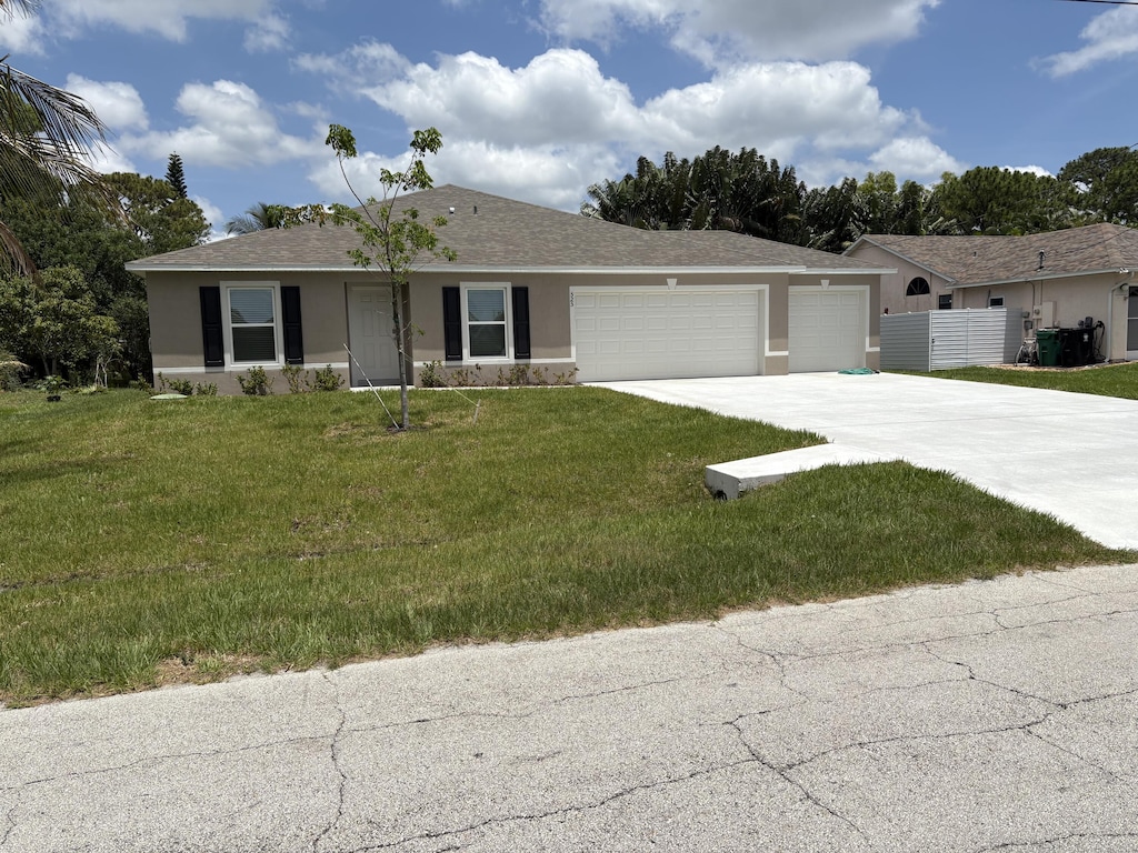 525 SE Fallon Dr, Port Saint Lucie, FL 34983 - ranch-style house with stucco siding, an attached garage, concrete driveway, a front yard, and roof with shingles