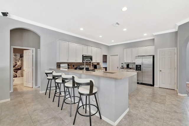 kitchen with visible vents, appliances with stainless steel finishes, arched walkways, a peninsula, and ornamental molding