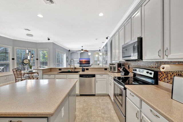 kitchen featuring a peninsula, recessed lighting, tasteful backsplash, a sink, and appliances with stainless steel finishes