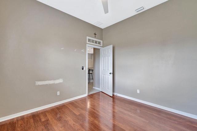 empty room with baseboards, visible vents, and wood finished floors