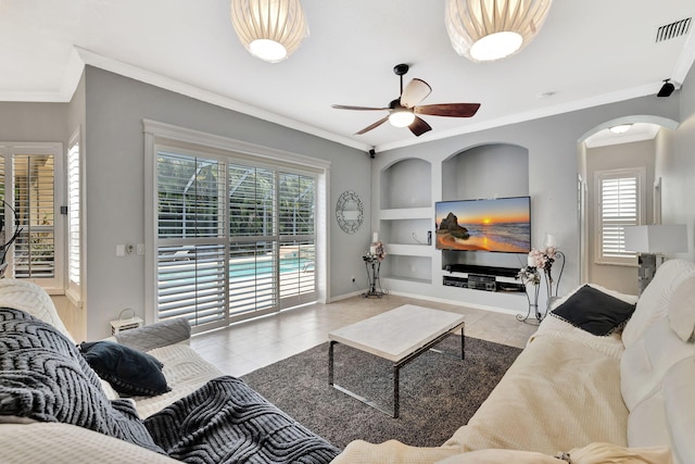 tiled living room with visible vents, crown molding, a healthy amount of sunlight, and built in shelves