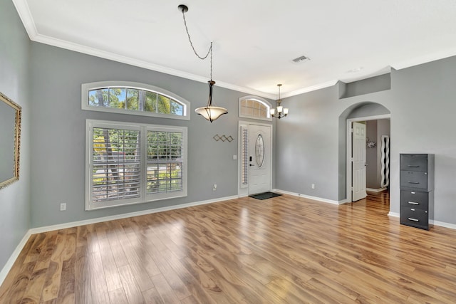 interior space with crown molding, arched walkways, baseboards, and light wood-style flooring