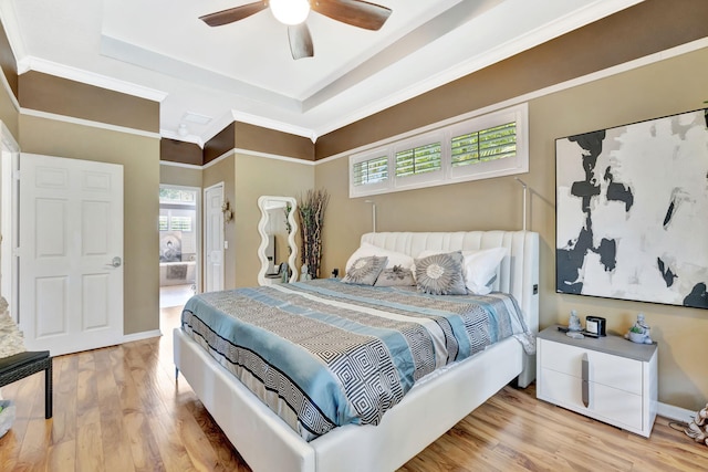 bedroom featuring a raised ceiling, multiple windows, ornamental molding, and wood finished floors