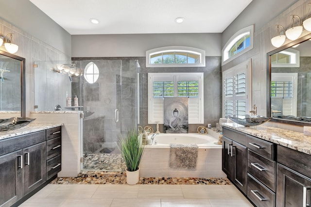 full bathroom featuring a sink, a shower stall, a garden tub, and two vanities