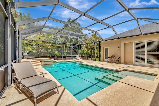 view of swimming pool featuring glass enclosure, a pool with connected hot tub, and a patio area