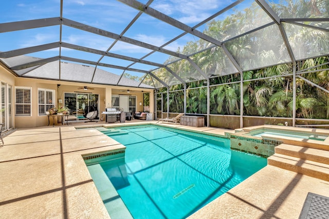 view of swimming pool with a ceiling fan, glass enclosure, a patio area, and a pool with connected hot tub
