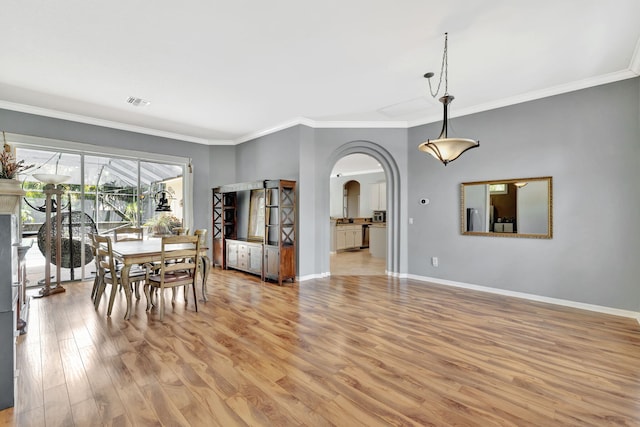 dining area featuring visible vents, crown molding, arched walkways, baseboards, and light wood-style floors