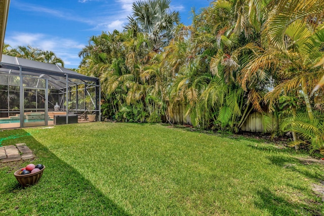 view of yard with an outdoor pool, a lanai, and fence