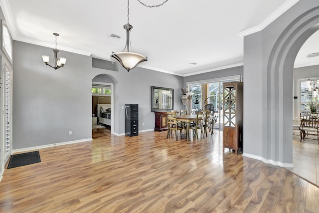 dining space featuring visible vents, arched walkways, light wood finished floors, and plenty of natural light