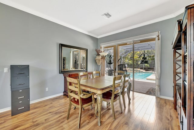 dining room with baseboards, ornamental molding, and light wood-style floors