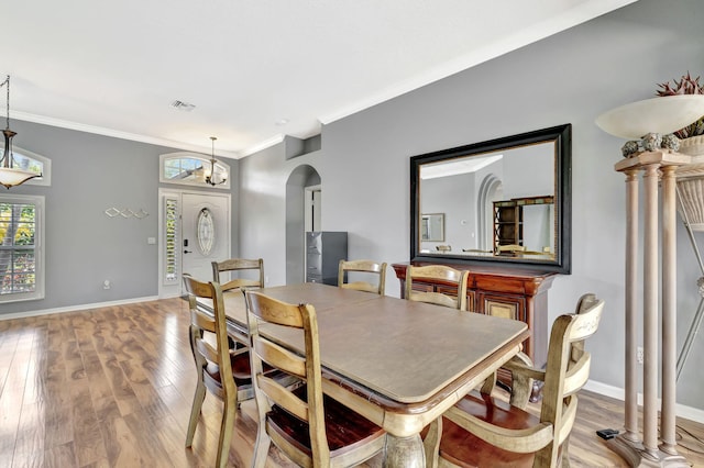 dining area with crown molding, visible vents, baseboards, arched walkways, and light wood finished floors