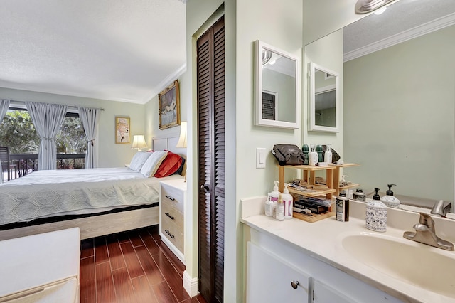 bedroom featuring ornamental molding, baseboards, access to outside, a sink, and dark wood finished floors