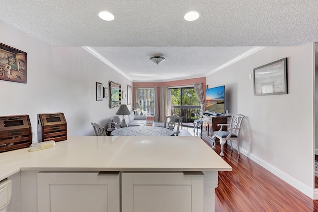 kitchen featuring dark wood-style flooring, light countertops, a textured ceiling, open floor plan, and ornamental molding