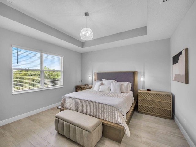 12495 SW Sunrise Lake Ter, Port Saint Lucie, FL 34987 - bedroom featuring light wood-type flooring, baseboards, and a tray ceiling