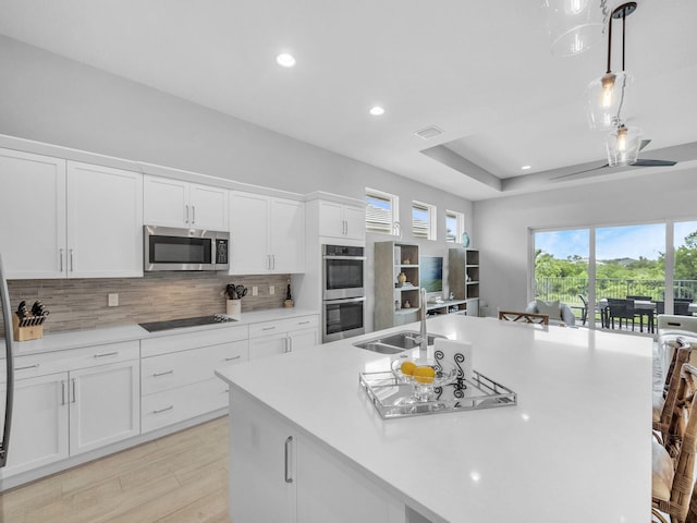 12495 SW Sunrise Lake Ter, Port Saint Lucie, FL 34987 - kitchen with appliances with stainless steel finishes, a sink, decorative backsplash, an island with sink, and light countertops